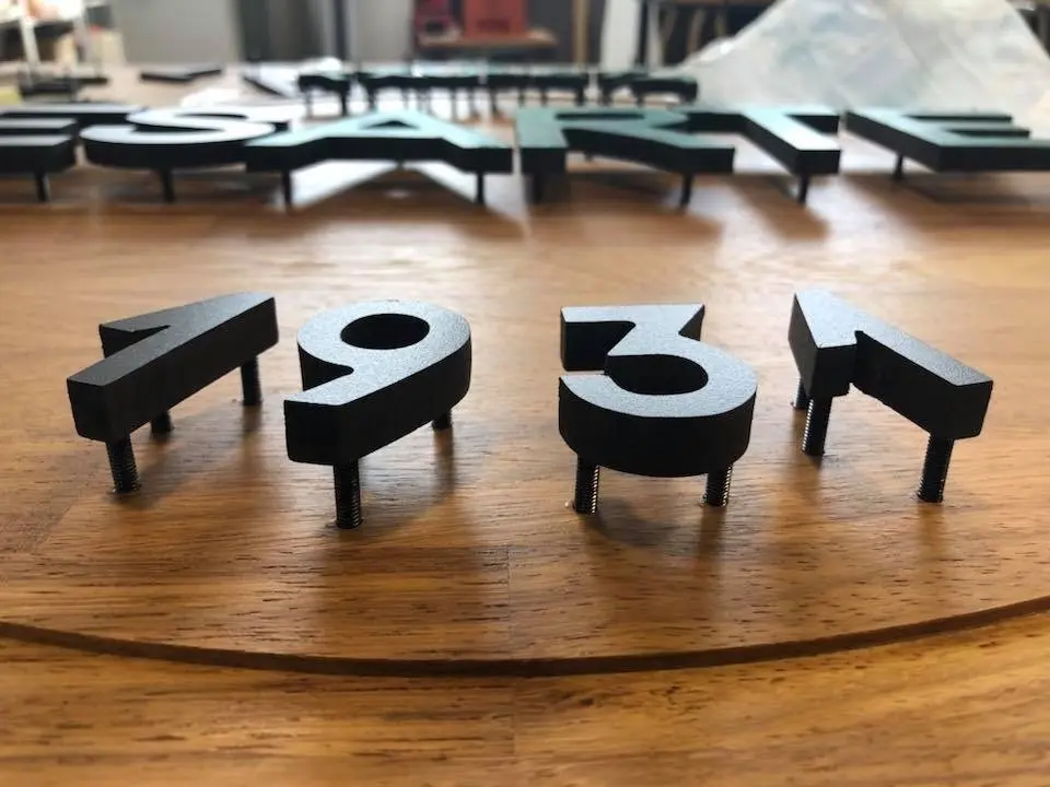 Letrero 3D de PVC lacadas colocadas con soportes sobre madera fresada